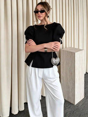 Detail of bow on sleeve of black peplum blouse