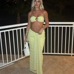 Woman in a light green outfit standing on a balcony at night.