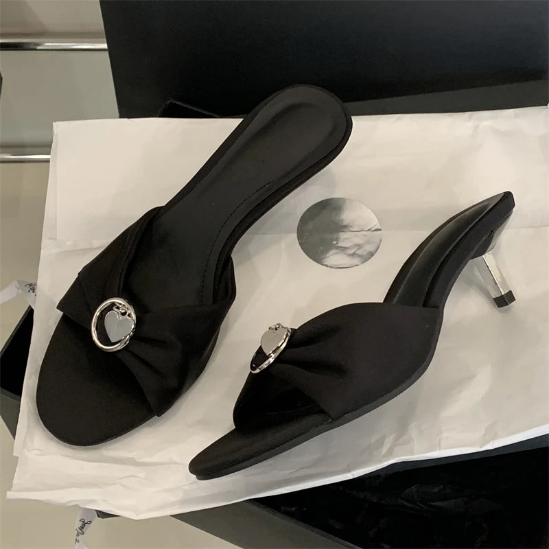 Black high-heeled shoes with decorative buckles on a white surface