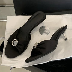 Black high-heeled shoes with decorative buckles on a white surface