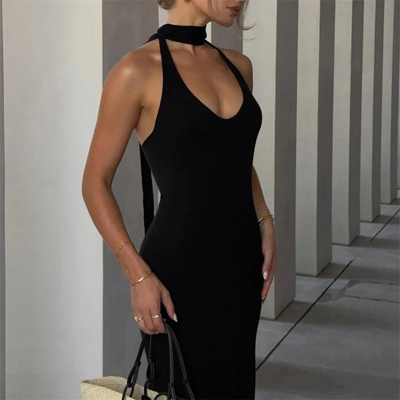 Woman wearing a black dress standing against a geometric wall.