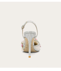 White high-heeled shoe with floral details on a light gray background