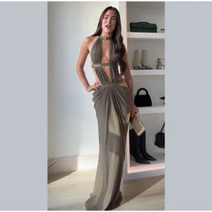 Woman in a long, elegant dress standing in a room with shelves displaying bags.