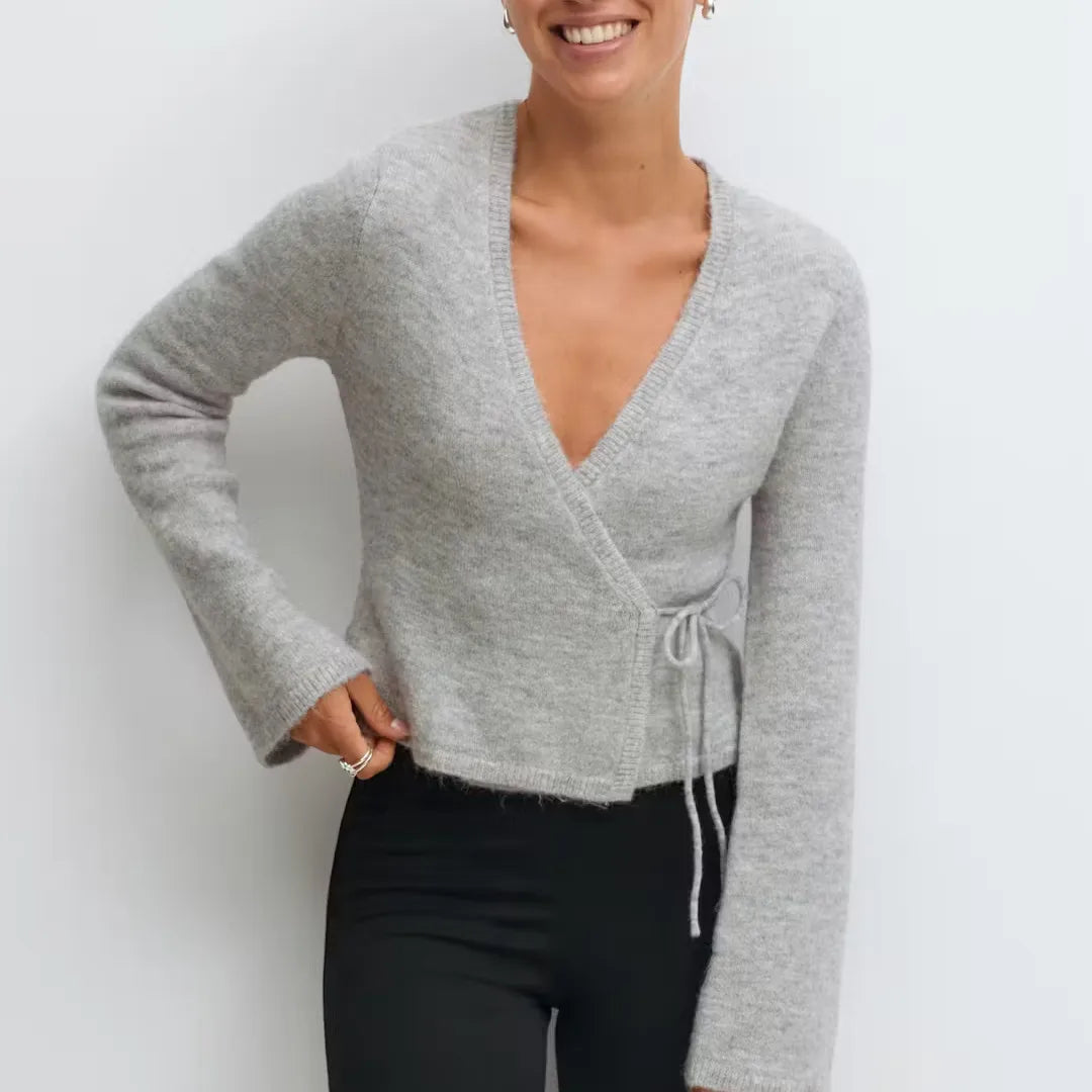 Person wearing a gray wrap-style sweater against a white background