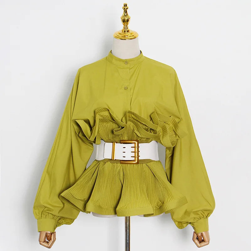 Green blouse with ruffled details and a white belt on a mannequin against a white background