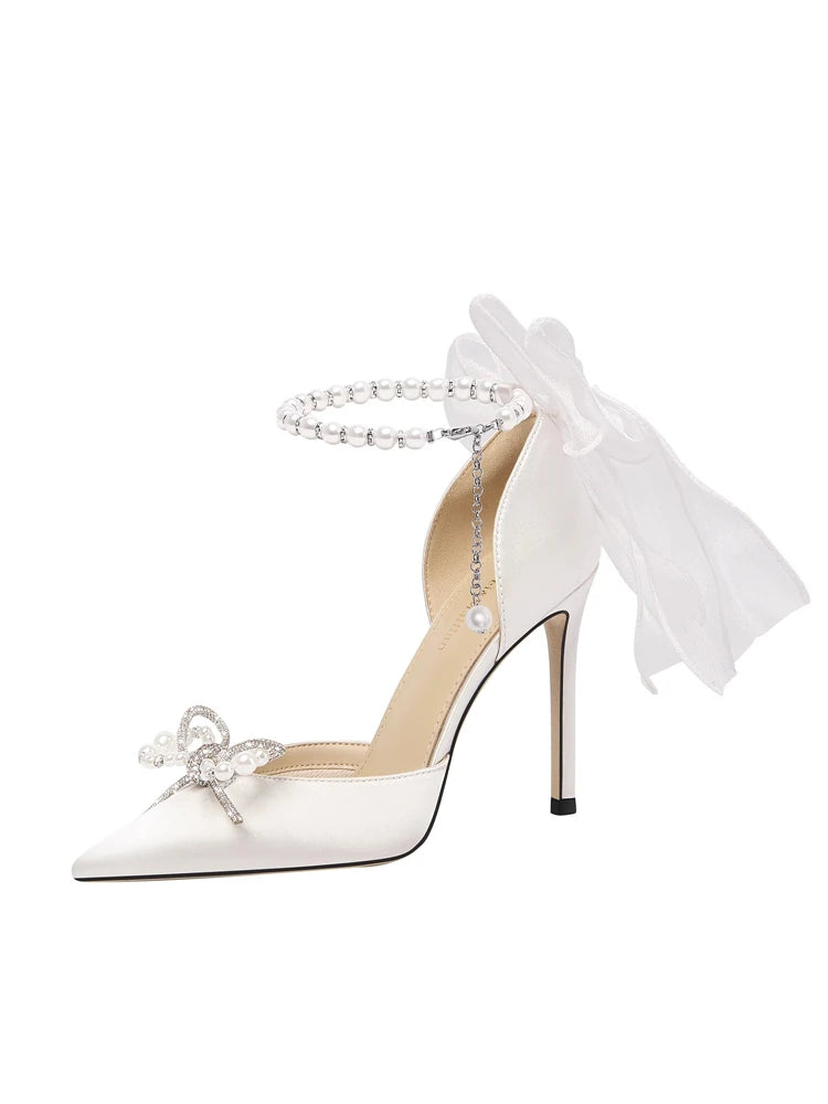 White high-heeled shoe with decorative bow and tassel on a white background
