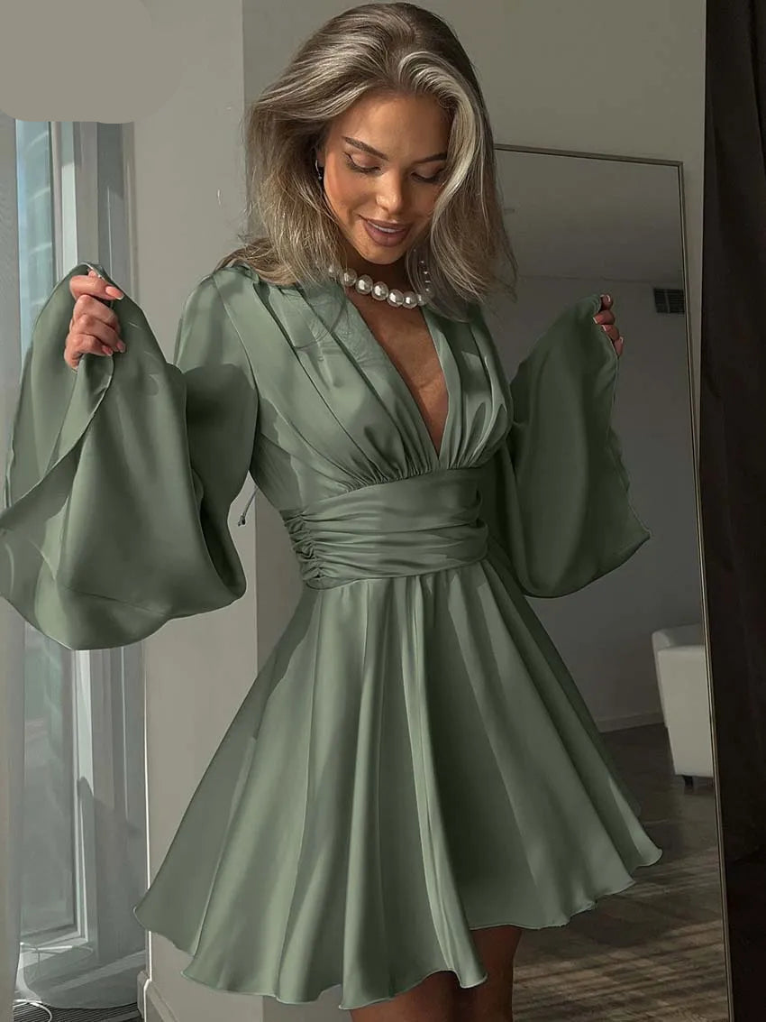 Woman wearing a green dress with bell sleeves in an indoor setting