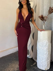 Woman in a burgundy dress standing next to a white textured column indoors.