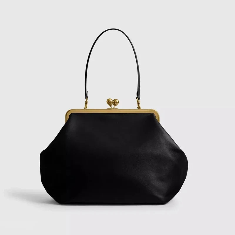 Black handbag with gold clasp on a light gray background