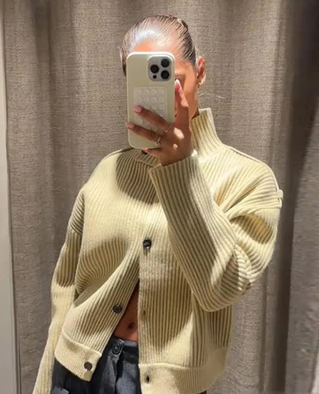 Person wearing a light green ribbed sweater taking a mirror selfie.