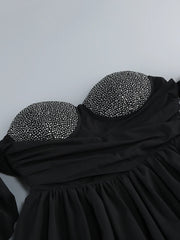 Black dress with embellished straps on a light gray background
