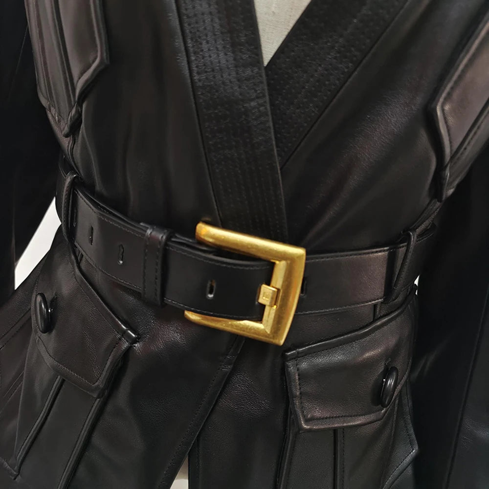 Close-up of a black leather outfit with a gold belt buckle on a neutral background