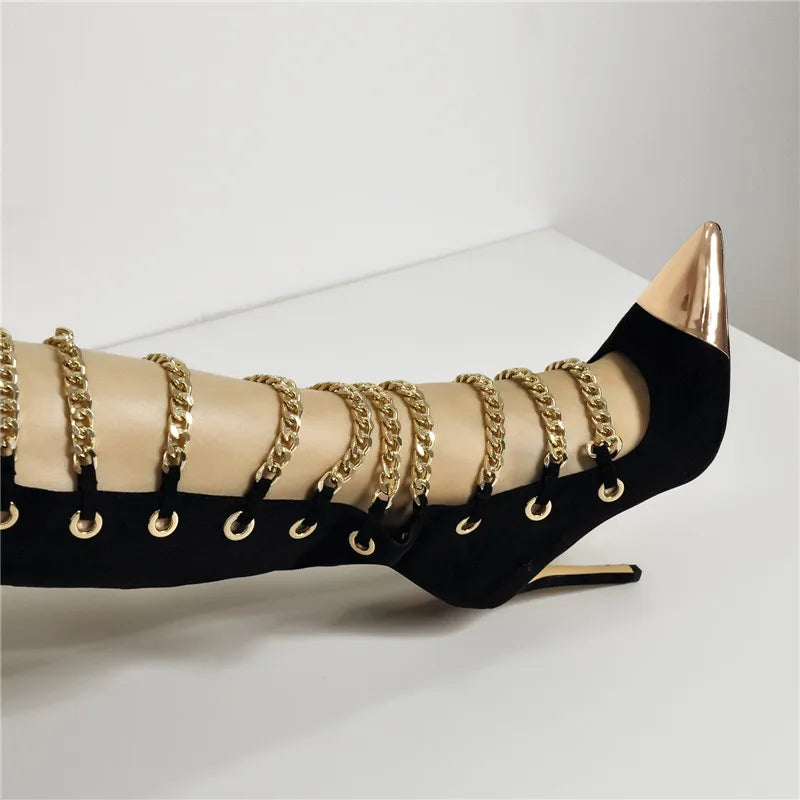 Black high-heeled shoe with gold chains on a white background