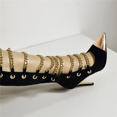 Black high-heeled shoe with gold chains on a white background