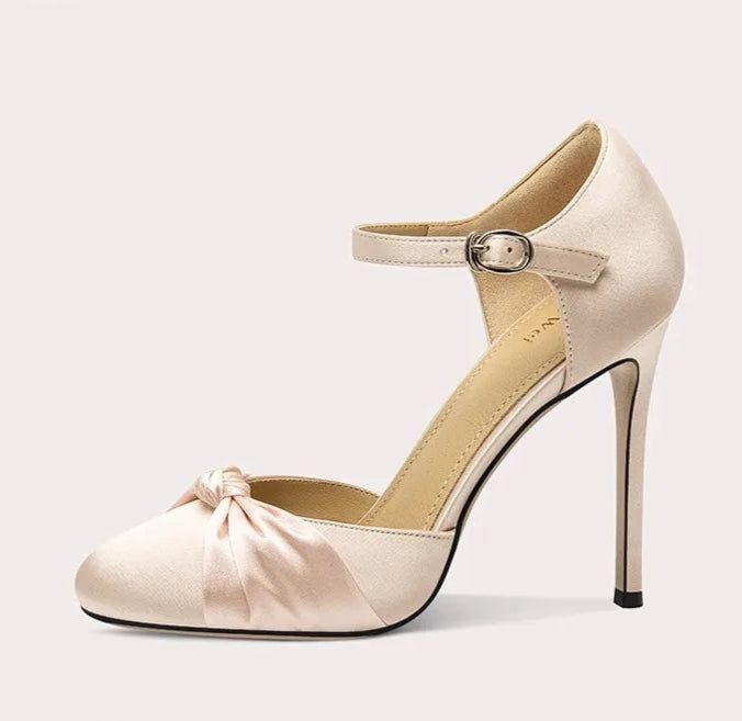 Beige high-heeled shoe with a bow on a light gray background