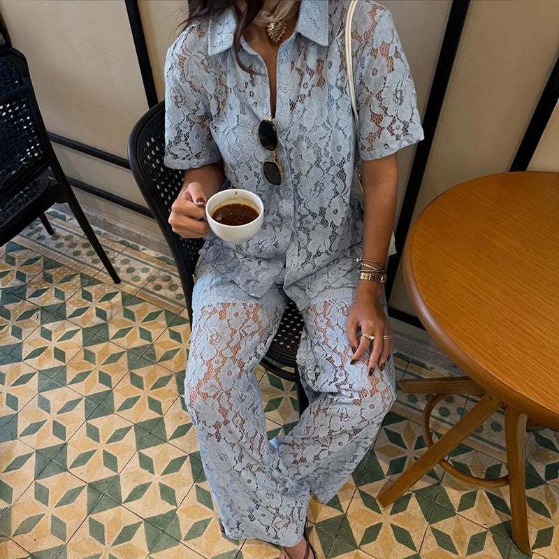 Person in a lace outfit holding a cup of coffee in a cafe.