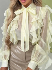Light green ruffled blouse with a bow tie worn by a person against a neutral background