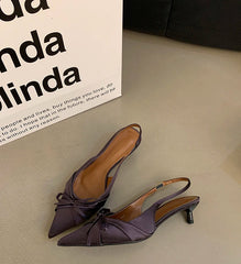 Pair of purple high-heeled shoes on a light surface with a blurred background