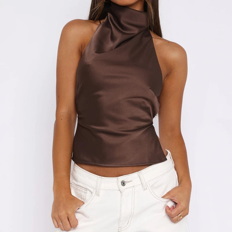 Woman wearing a brown halter top and white pants on a white background