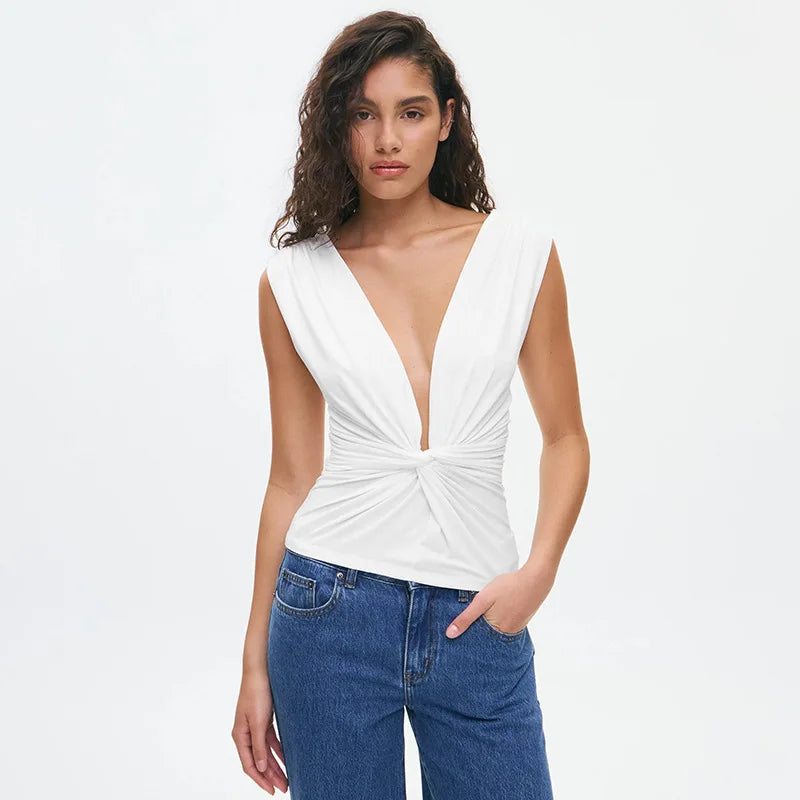 Woman wearing a white sleeveless top with a deep neckline and blue jeans on a white background