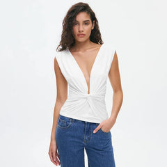 Woman wearing a white sleeveless top with a deep neckline and blue jeans on a white background