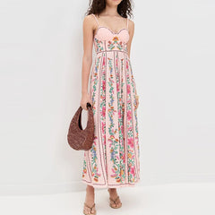 Woman wearing a floral dress holding a woven bag against a white background