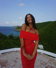 Woman in a red dress standing on a balcony with ocean and island view