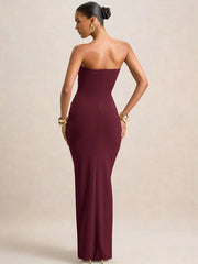 Woman wearing a burgundy strapless gown against a beige background