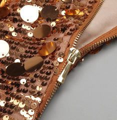 Close-up of a rose gold sequin pouch with a gold zipper on a gray background