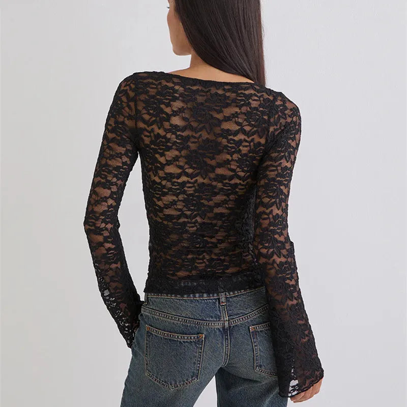 Person wearing a black lace long-sleeve top over a denim jacket on a light gray background