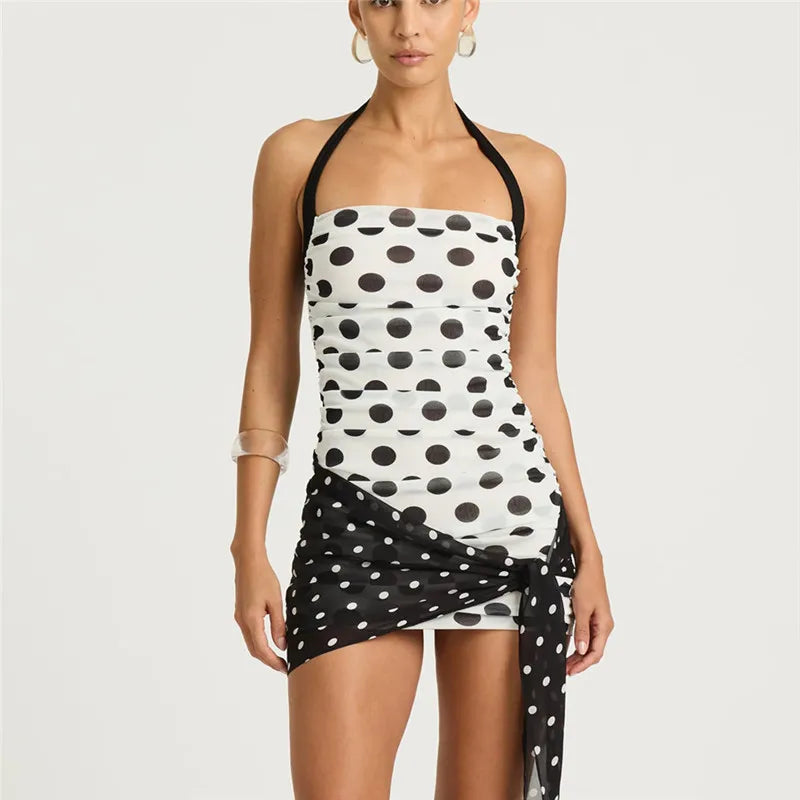 Woman wearing a black and white polka dot dress on a plain background