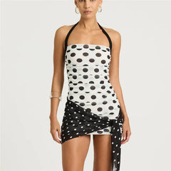 Woman wearing a black and white polka dot dress on a plain background