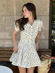 Woman wearing a floral dress standing against a textured wall.