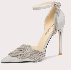Silver high-heeled shoe with decorative bow on a white background