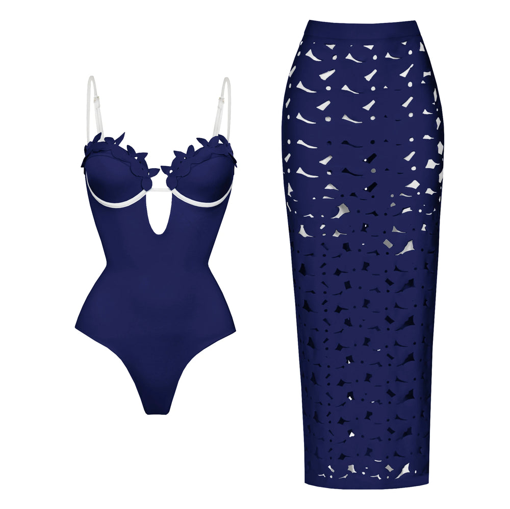 Dark blue one-piece swimsuit with floral appliqué neckline and contrast trim, paired with a matching laser-cut maxi skirt.
