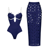 Dark blue one-piece swimsuit with floral appliqué neckline and contrast trim, paired with a matching laser-cut maxi skirt.