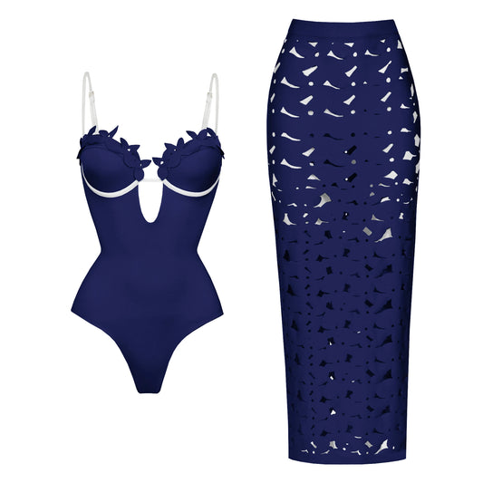 Dark blue one-piece swimsuit with floral appliqué neckline and contrast trim, paired with a matching laser-cut maxi skirt.