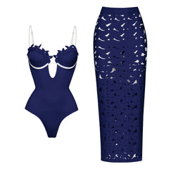 Dark blue one-piece swimsuit with floral appliqué neckline and contrast trim, paired with a matching laser-cut maxi skirt.