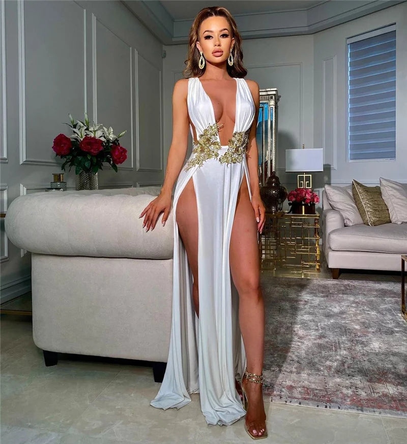 Woman in a white and gold dress standing in a stylish living room.