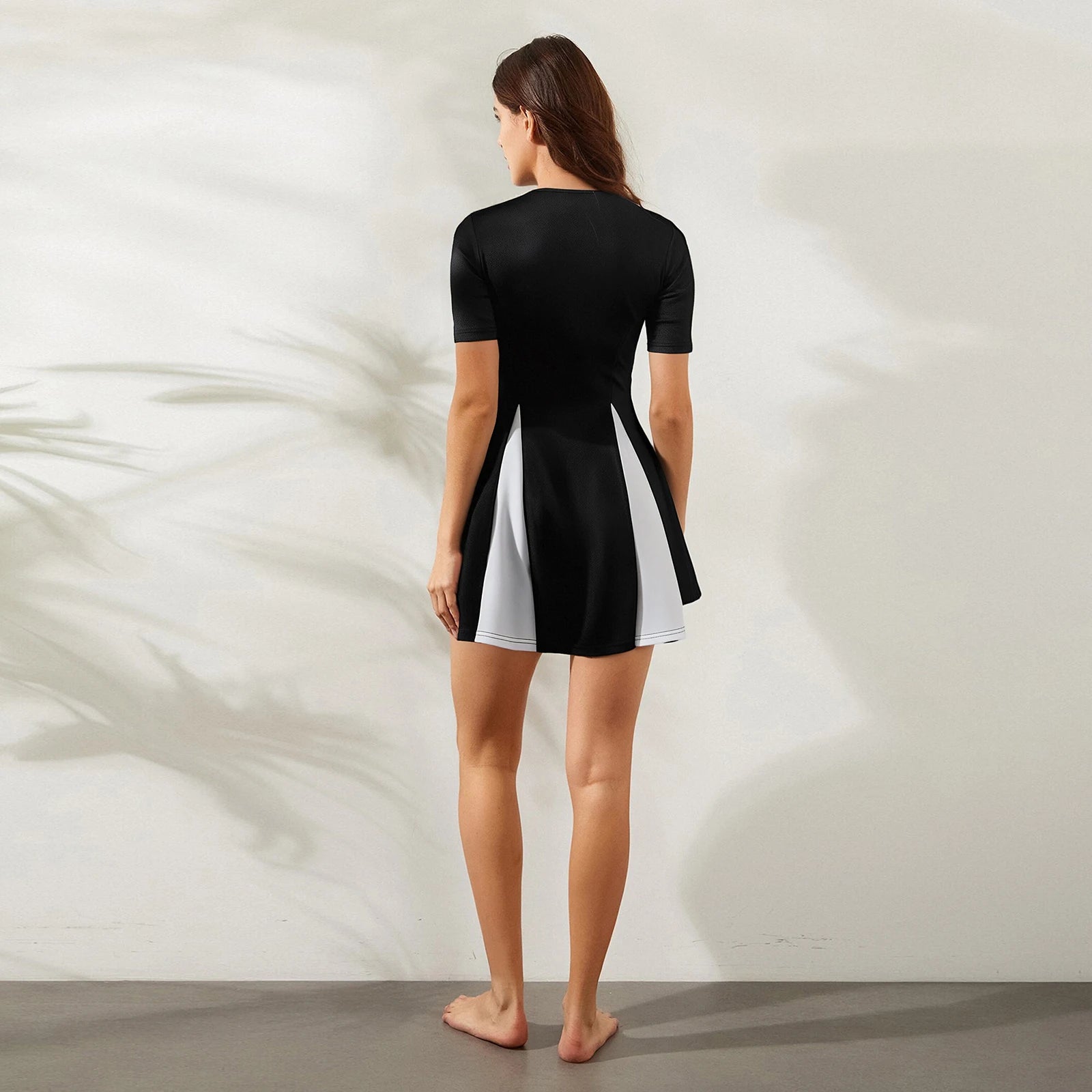 Woman wearing a black and white dress against a neutral background