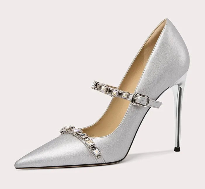 Silver high-heeled shoe with decorative strap on a light gray background