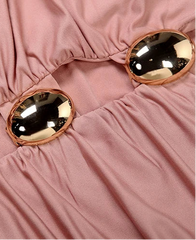 Close-up of a pink fabric with gold buttons on a pink background