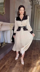 Woman wearing a polka dot dress with black lace details in an elegant room.