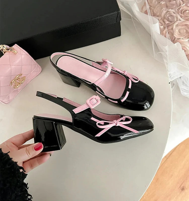 Black patent leather chunky Mary Jane heels with pink trim and bowknot detail.