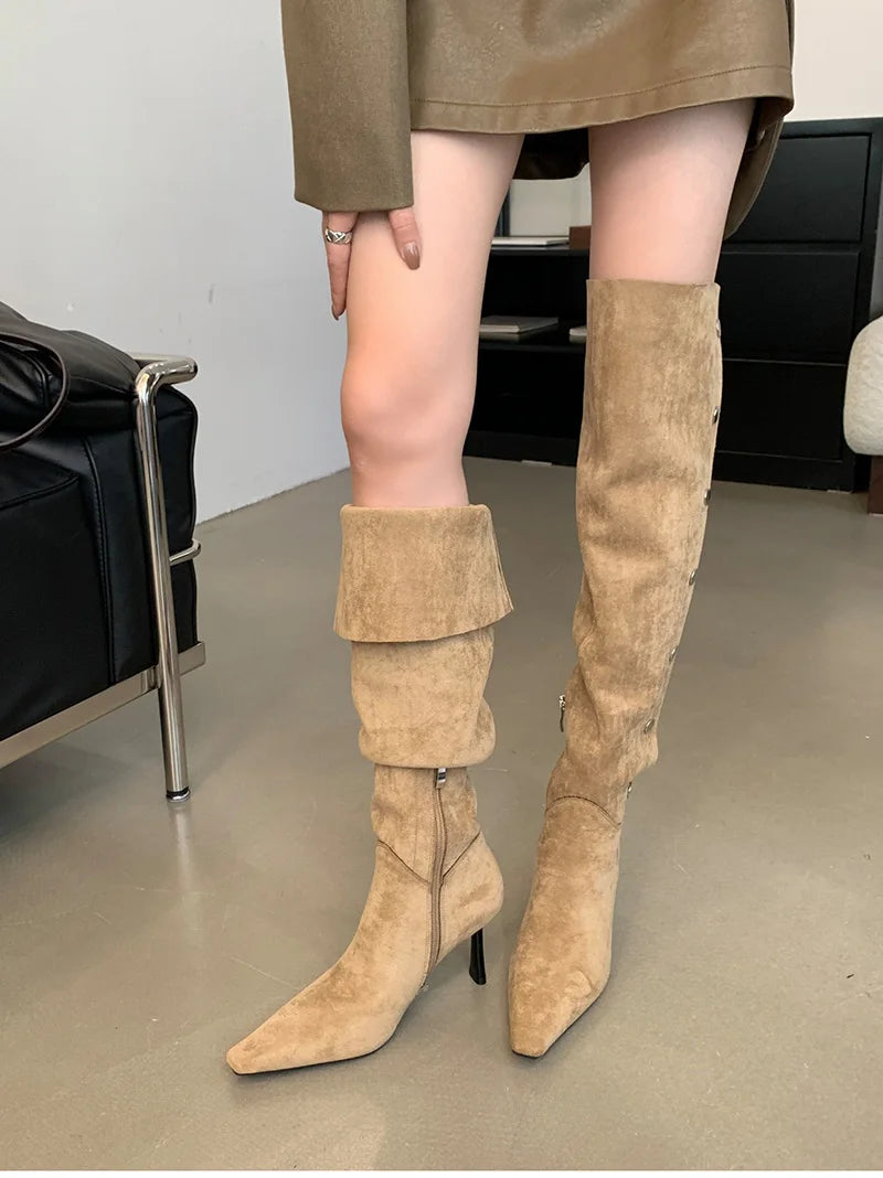 Beige suede knee-high boots worn indoors on a neutral background