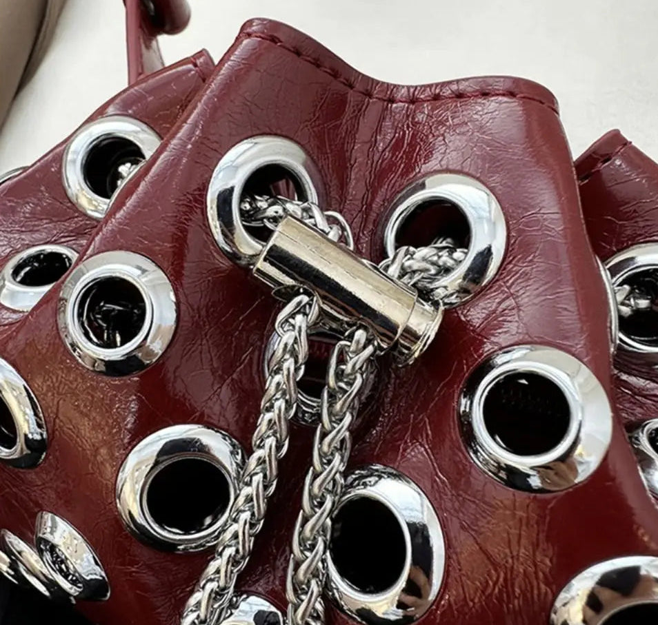 Close-up of a red leather boot with silver eyelets and chain detail.