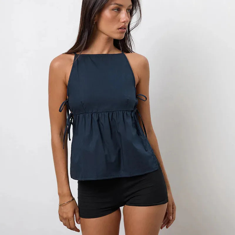 Woman wearing a navy blue sleeveless top and black shorts on a plain background