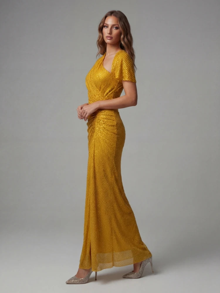 Woman wearing a gold evening gown on a grey background