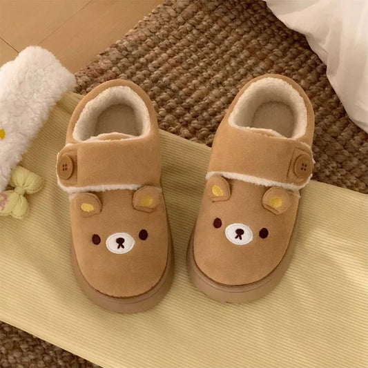 Brown cartoon bear house slippers on a woven rug.