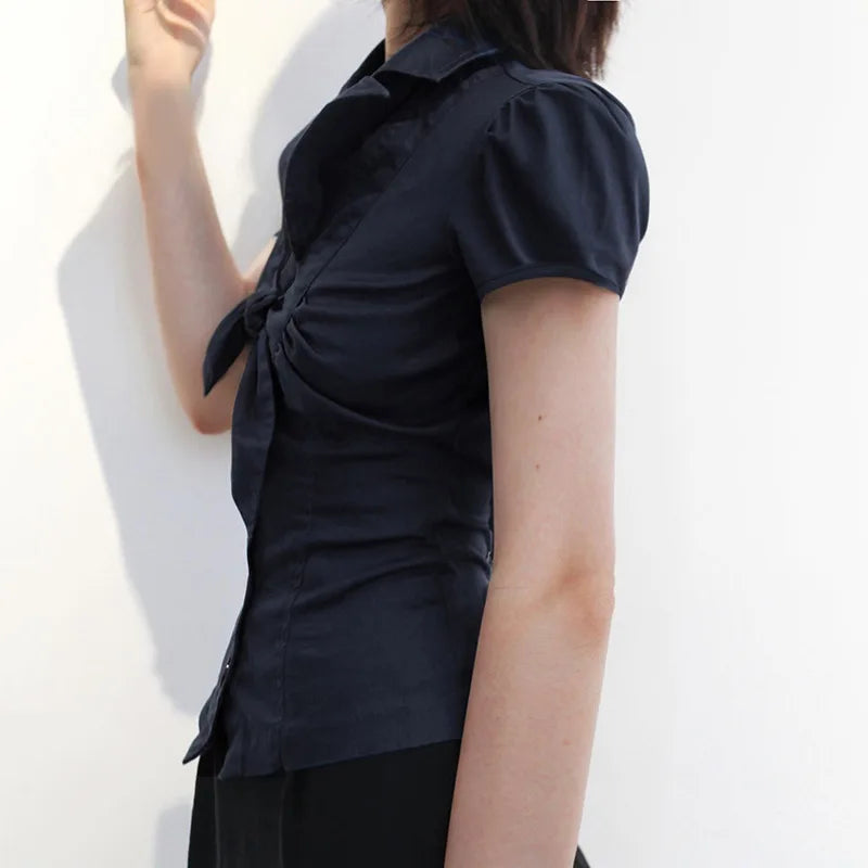 Person wearing a black short-sleeve shirt with a knot detail on a white background